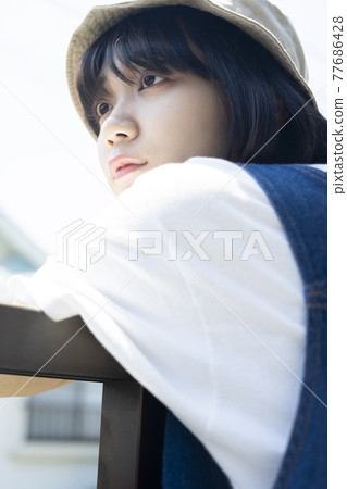 Woman relaxing on the veranda 77686428