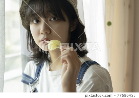 Woman eating ice cream by the window 77686453