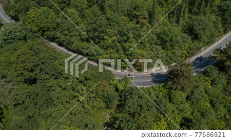 Aerial view from above of curve road with a car on the mountain with green forest in Russia 77686921
