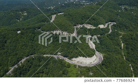 Aerial view from above of curve road with a car on the mountain with green forest in Russia 77686924