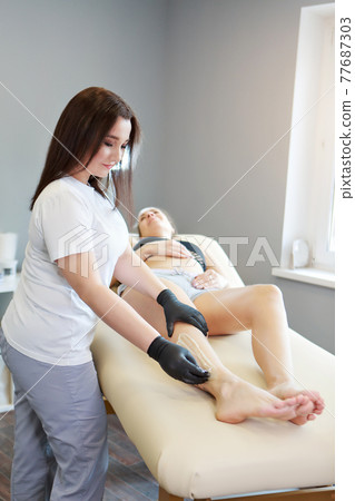 Hands in rubber gloves close-up. doctor puts wax, honey. medic is preparing for depilation. Concept of medicine, health care, beauty industry, hair removal, natural material. Copy space 77687303