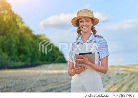 Woman farmer straw hat smart farming standing farmland smiling using digital tablet Female agronomist specialist research monitoring analysis data agribusiness Woman farmer straw hat smart farming standing farmland smiling using digital tablet Female agronomist specialist research monitoring analysis data agribusiness 77687408