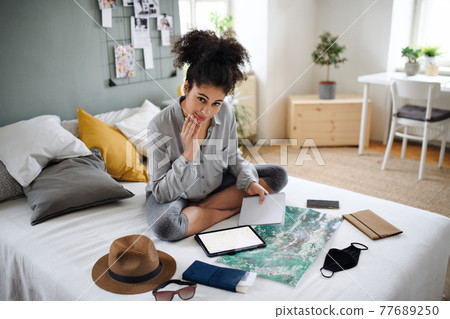 Young woman with tablet and map indoors at home, planning traveling trip. Young woman with tablet and map indoors at home, planning traveling trip. 77689250
