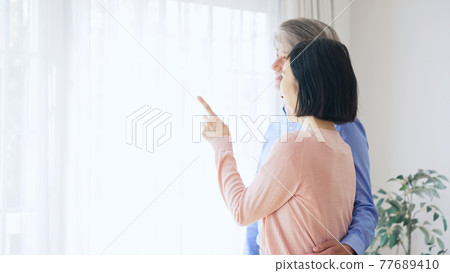 Senior couple looking out the window Senior couple looking out the window 77689410