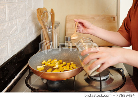 Woman cooking food in frying pan Woman cooking food in frying pan 77689484