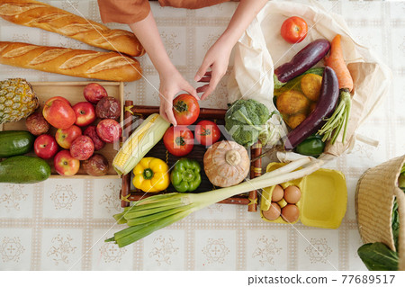 Woman unpacking recyclable grocery bags Woman unpacking recyclable grocery bags 77689517
