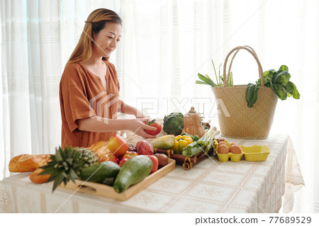 Woman unpacking bags of groceries 77689529