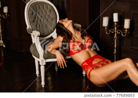 Beautiful young woman in sexual red lingerie and white shirt posing in Christmas decorations. Beautiful young woman in sexual red lingerie and white shirt posing in Christmas decorations. 77689803
