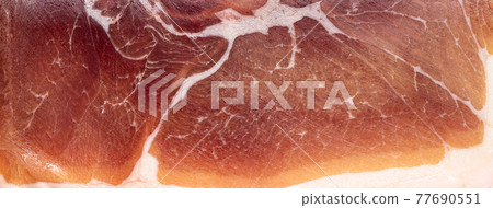 Jamon or dry-cured ham produced in Spain texture close up. Food background Jamon or dry-cured ham produced in Spain texture close up. Food background 77690551
