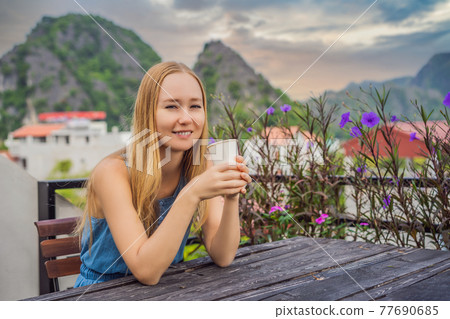 Woman drinks coffee in the morning on the background of hills in Ninh Binh, Tam Coc. Resumption of tourism in Vietnam after quarantine Coronovirus COVID 19 77690685