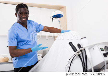 Smiling African American cosmetologist inviting to aesthetic medicine clinic Smiling African American cosmetologist inviting to aesthetic medicine clinic 77690997