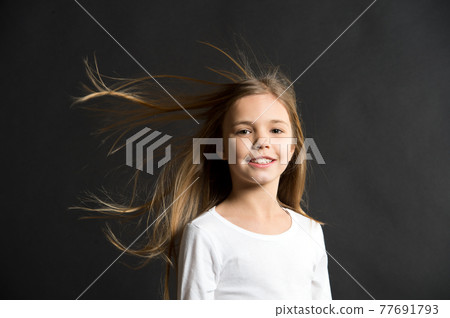 Natural beauty. Girl kid long hair flying in air, black background. 77691793