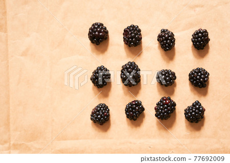Twelve blackberries on a beige craft paper background, form of a rectangle 77692009