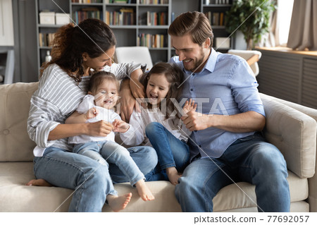 Overjoyed parents play with small daughters 77692057