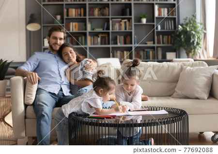 Happy young family with kids relax in living room 77692088