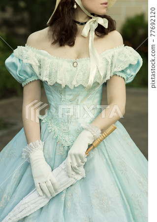 A beautiful young woman in a historical blue dress 1860 year. Book cover design. A beautiful young woman in a historical blue dress 1860 year. Book cover design. 77692120
