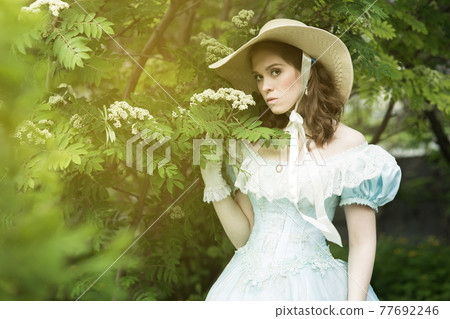 A beautiful young woman in a historical blue dress 1860 year. Book cover design. A beautiful young woman in a historical blue dress 1860 year. Book cover design. 77692246