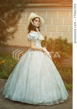 A beautiful young woman in a historical blue dress 1860 year. Book cover design. A beautiful young woman in a historical blue dress 1860 year. Book cover design. 77692303