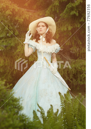 A beautiful young woman in a historical blue dress 1860 year. Book cover design. A beautiful young woman in a historical blue dress 1860 year. Book cover design. 77692356