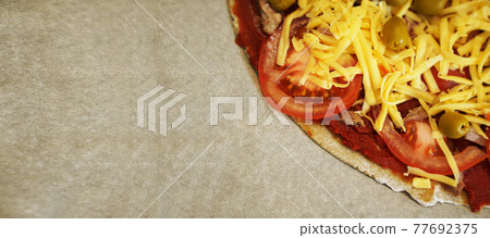 Pizza with beef on baking paper prepared for baking. Cooking at home. Banner 77692375