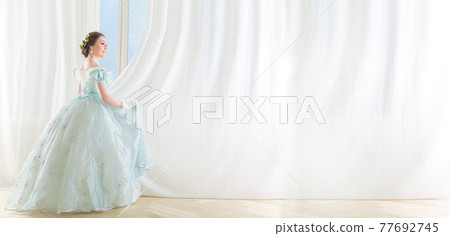 Beautiful elegant dark haired woman in historic dress on background with window 77692745