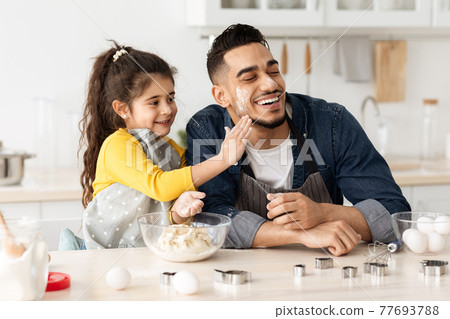 Cheerful Middle Eastern Dad And Daughter Having Fun While Baking In Kitchen 77693788