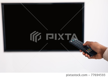 Black guy watching TV and using remote controller 77694593