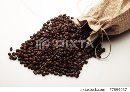 Roasted coffee beans scattered of the burlap bag isolated on white 77694987