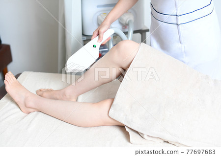 Young woman undergoing leg hair removal Young woman undergoing leg hair removal 77697683
