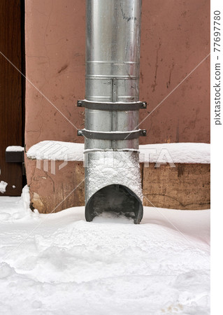 Metal water pipe on the corner of the house is filled with snow Metal water pipe on the corner of the house is filled with snow 77697780