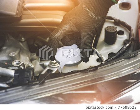 The mechanic's hand was open or closed cap to the water reserve tank of the car wiper The mechanic's hand was open or closed cap to the water reserve tank of the car wiper 77699522