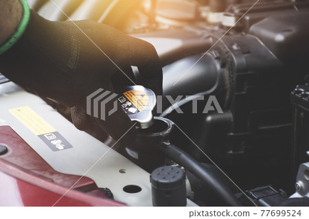 Mechanic hand was opening the radiator cap to check the coolant level of the car radiator Mechanic hand was opening the radiator cap to check the coolant level of the car radiator 77699524