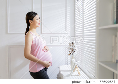 asian pregnant woman near windows 77699621