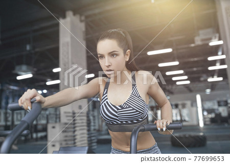 Young woman exercises in gym healthy lifestyle intense cardio cl Young woman exercises in gym healthy lifestyle intense cardio cl 77699653