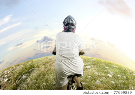 Rear view of Asian woman with a bicycle helmet riding a bicycle Rear view of Asian woman with a bicycle helmet riding a bicycle 77699889