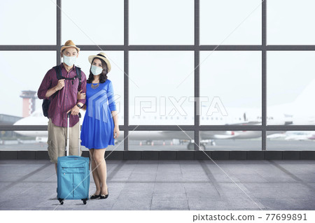 Asian couple in the face mask with suitcase bag and backpack standing 77699891