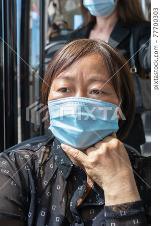 Mature asian woman wearing a mask on a bus: Selective focus. Safety and new public transport rules concept. Mature asian woman wearing a mask on a bus: Selective focus. Safety and new public transport rules concept. 77700303