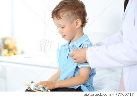 Happy smiling male kid-patient at usual medical inspection. Doctor and young boy in the clinic. Medicine concepts Happy smiling male kid-patient at usual medical inspection. Doctor and young boy in the clinic. Medicine concepts 77700717