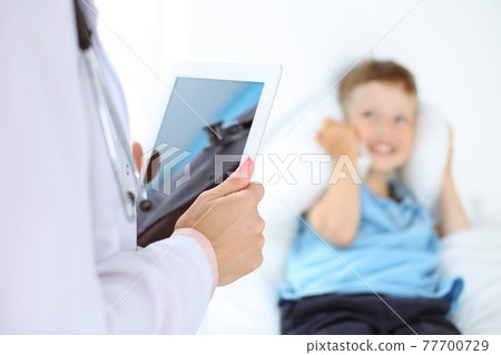Happy smiling male kid-patient at usual medical inspection. Doctor and young boy in the clinic. Medicine concepts Happy smiling male kid-patient at usual medical inspection. Doctor and young boy in the clinic. Medicine concepts 77700729