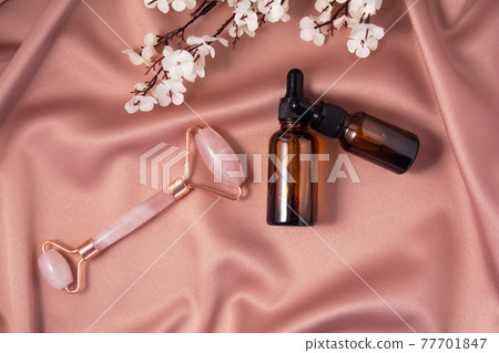 Quartz roller and cometic product on shiny pink fabric. Quartz roller and cometic product on shiny pink fabric. 77701847