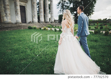 Happy wedding couple walking in a botanical park Happy wedding couple walking in a botanical park 77702570
