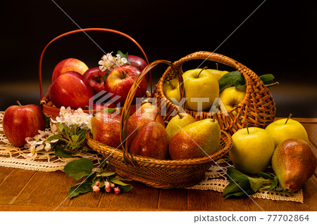 Fresh apples with apples blossoms on a dramatic dark wood background. Naturmort made from pears in a glass bowl. 77702864