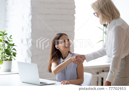 Smiling diverse female colleagues handshake in office 77702953