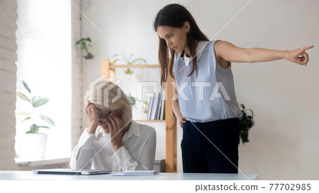 Angry young businesswomen fire middle-aged female employee 77702985