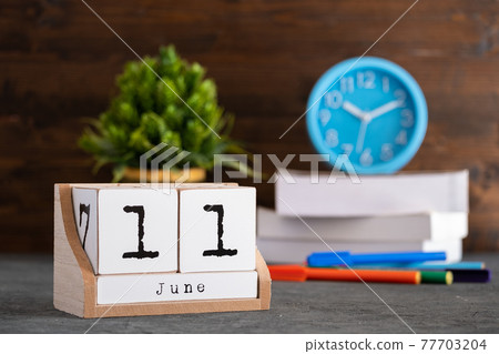 June 11th. June 11 wooden cube calendar with blur objects on background. June 11th. June 11 wooden cube calendar with blur objects on background. 77703204