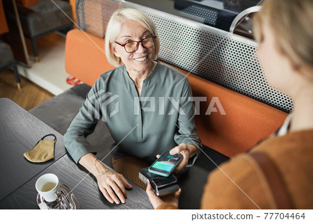 Positive cafe guest paying with gadget 77704464