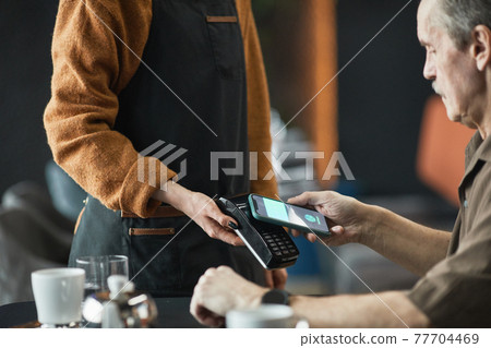 Using NFC on smartphone while paying in cafe Using NFC on smartphone while paying in cafe 77704469