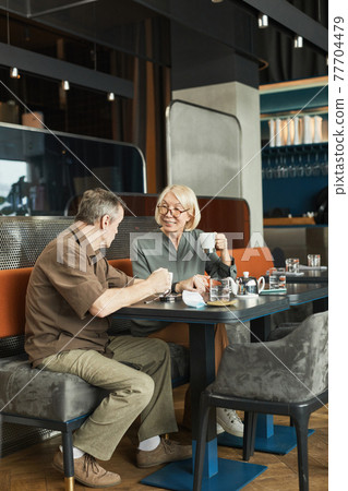 Positive senior man talking to friend in cafe 77704479