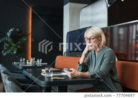 Serious senior lady scrolling on social media Serious senior lady scrolling on social media 77704697