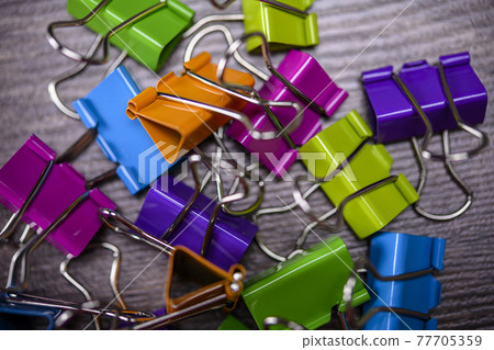 Bunch of multicolored binder clips on table Bunch of multicolored binder clips on table 77705359